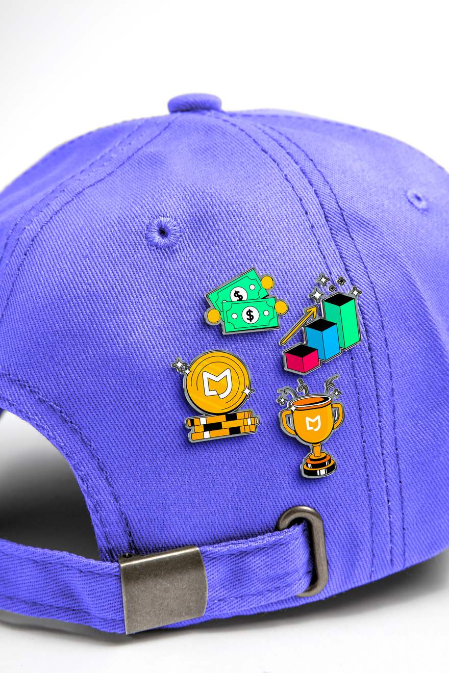Pins da gamificação Maggu, com troféu e moedas, em boné lilás